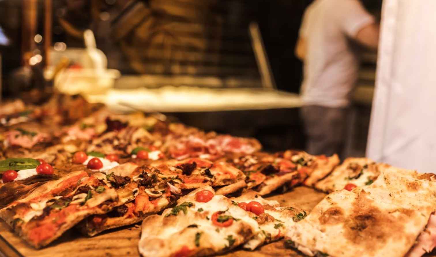 Display of various pizzas on a wooden counter in Bologna