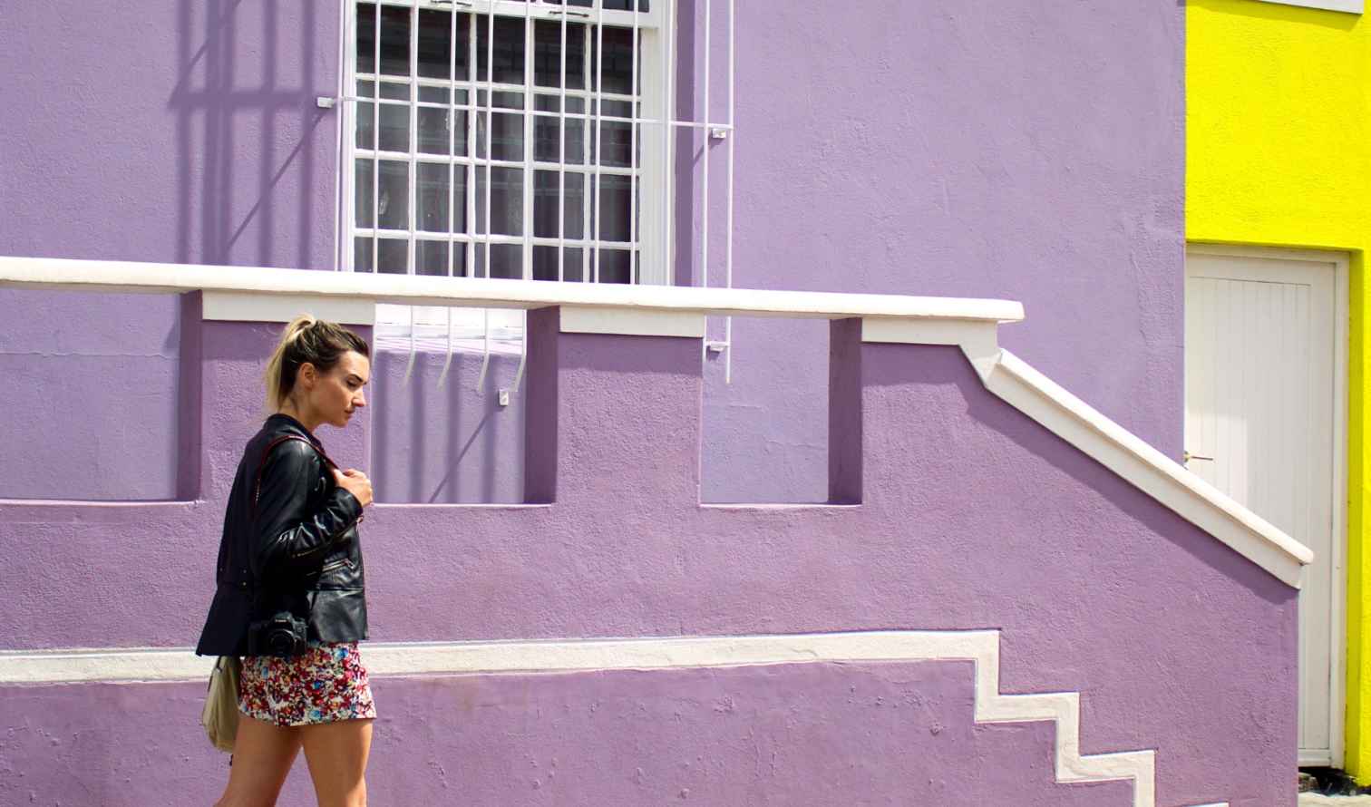 A woman walks past a purple and yellow building in Bo-Kaap, Cape Town.
