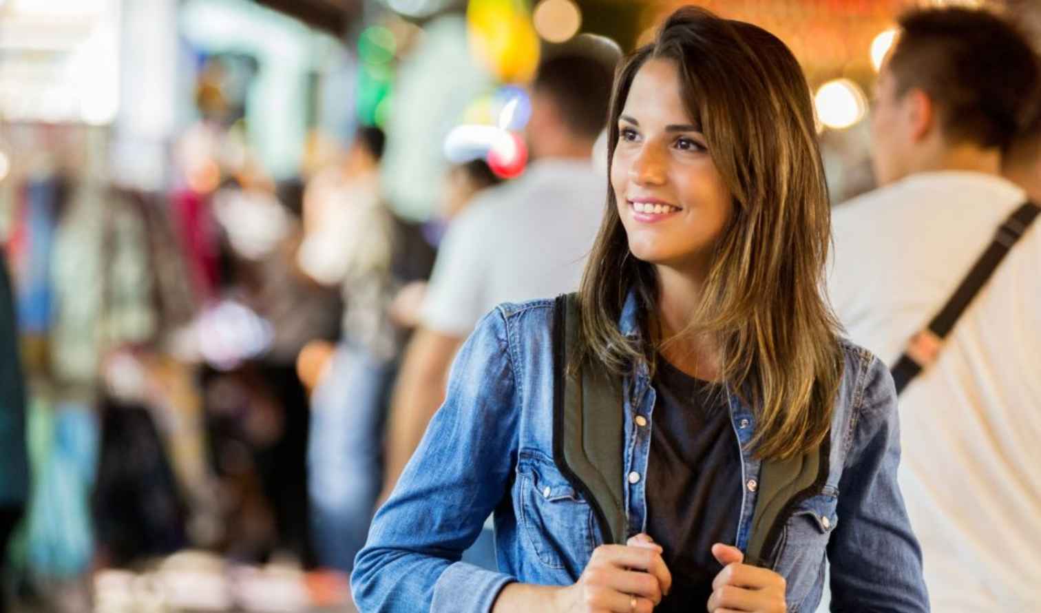 Woman in denim jacket walking through a busy market in Singapore