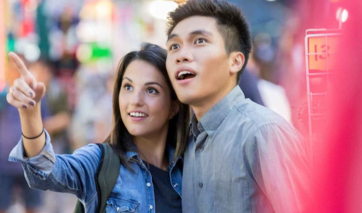 Two people looking and pointing at something in a crowded place in Singapore
