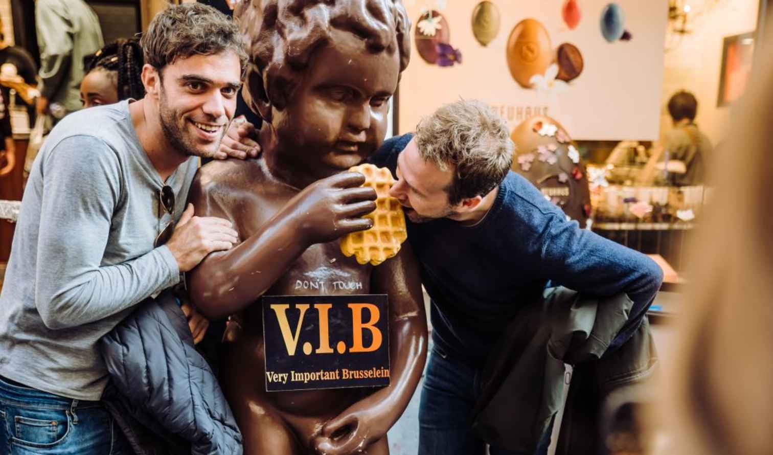 Two people interacting with a chocolate statue in Brussels.
