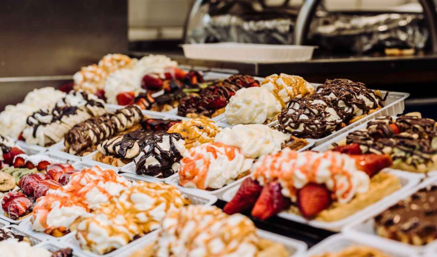 Plates of waffles topped with whipped cream and various chocolate sauces in Brussels