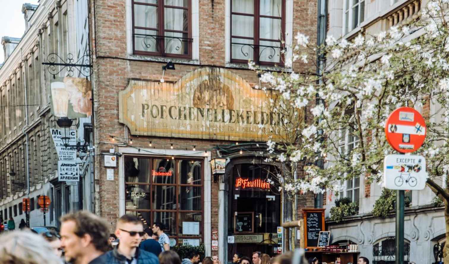 Facade of Poechenellekelder pub in Brussels with street signs.