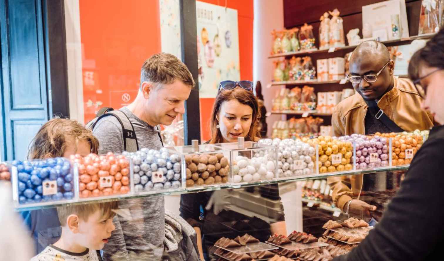 People browsing colorful chocolates at a display in a candy store in Brussels