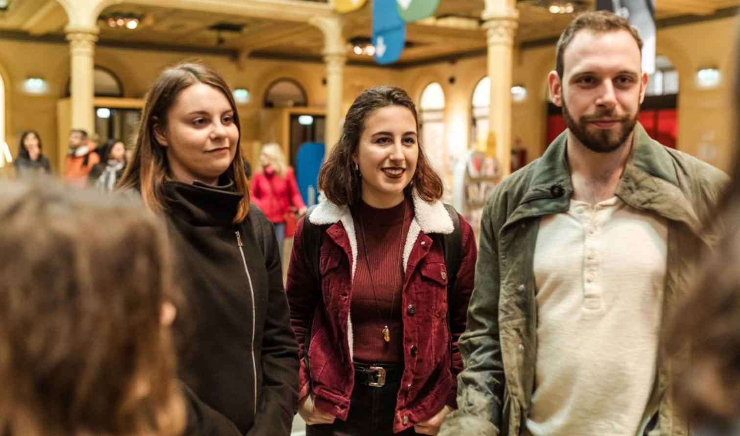 Group of people standing inside a historic building with columns and arches in Bologna