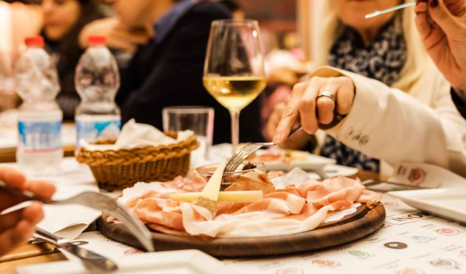 Restaurant patrons enjoying a charcuterie board with wine in Bologna