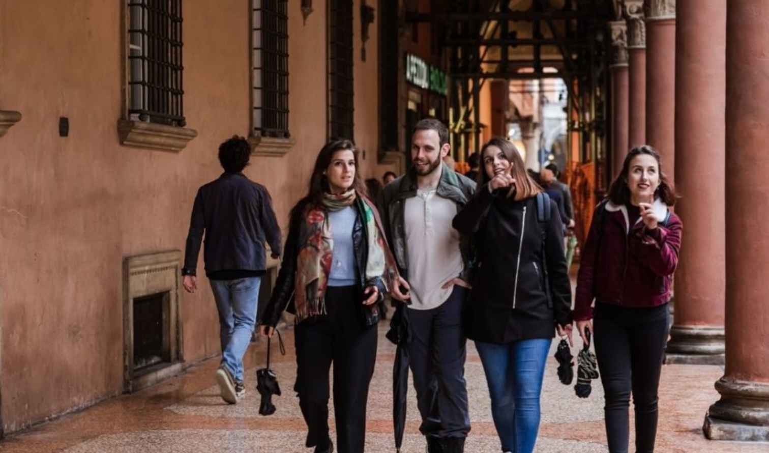 Group of people walking under the porticoes in Bologna, Italy.