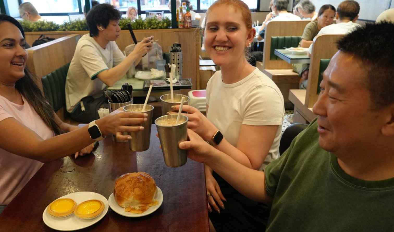 People toasting with drinks at a Hong Kong-style cafe.