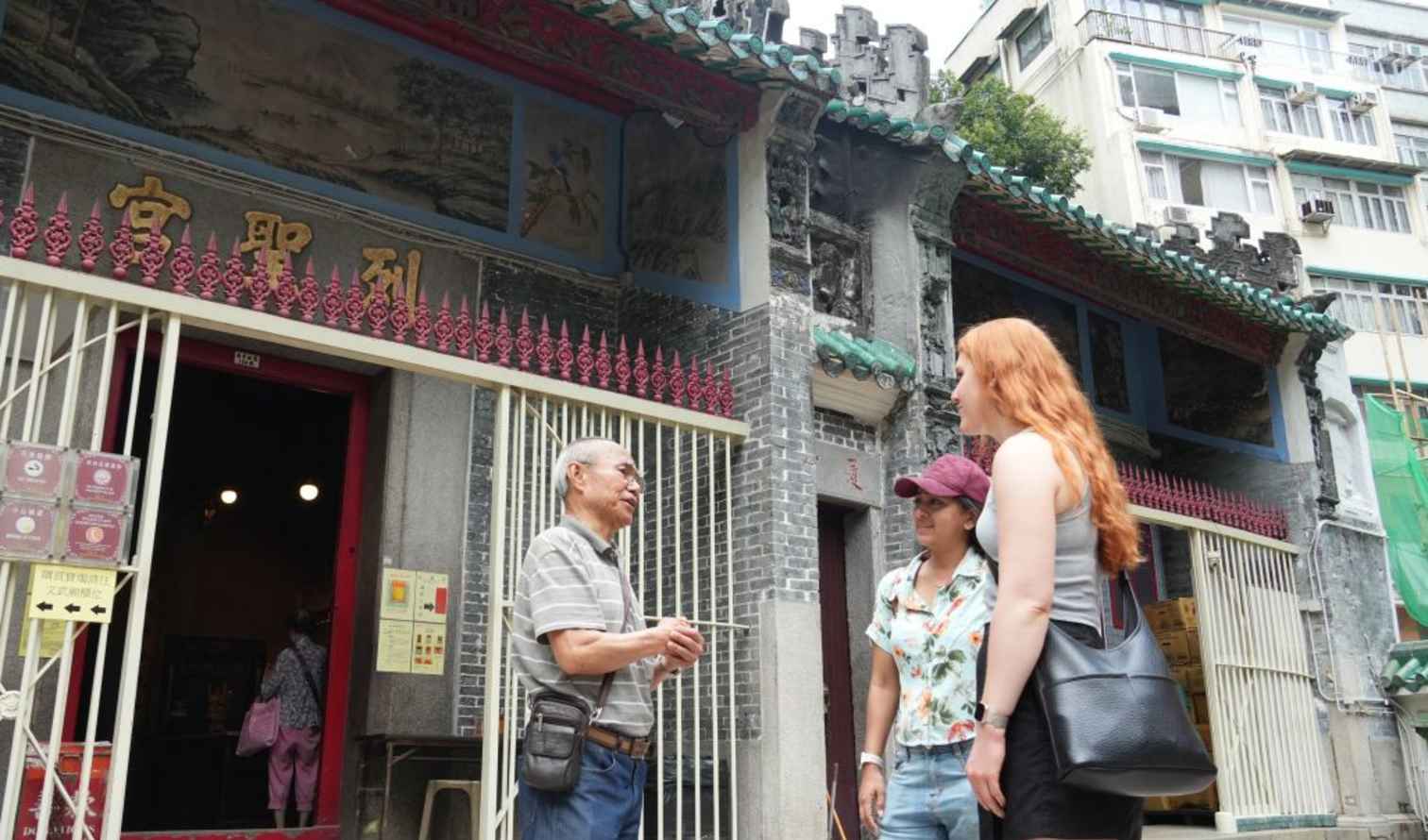 Three people stand outside Tin Hau Temple in Hong Kong.