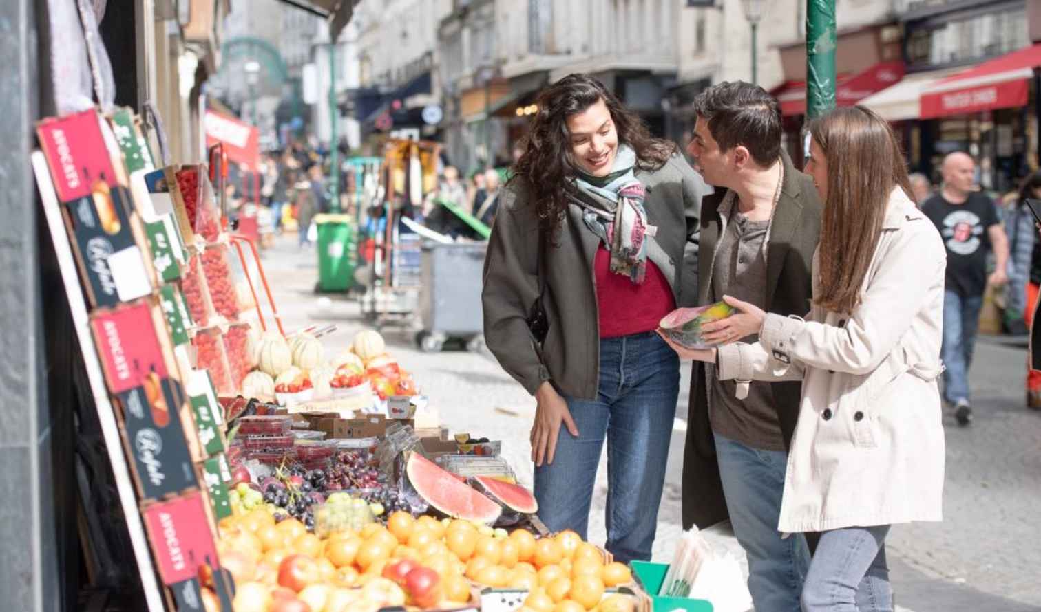 People shopping at a street market lined with vendor stalls in Paris