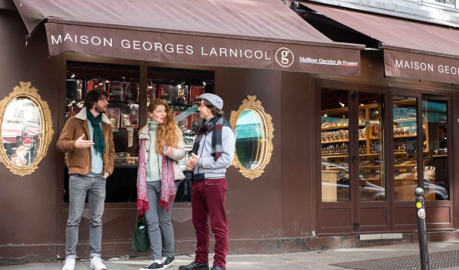 Three people standing outside Maison Georges Larnicol in Paris, France.
