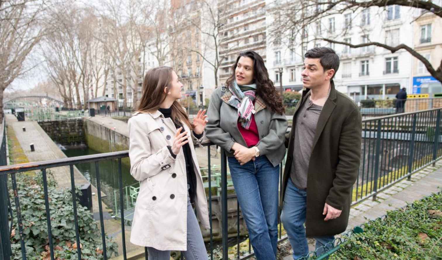 Three people standing near Canal Saint-Martin in Paris, France.