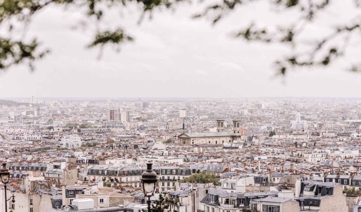 Panoramic view of Paris cityscape with Sacré-Cœur Basilica in the distance.