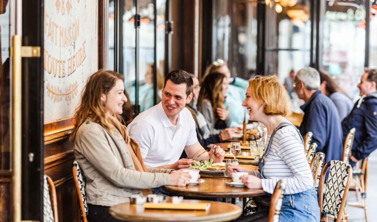 People sitting at a Parisian café on a busy street.