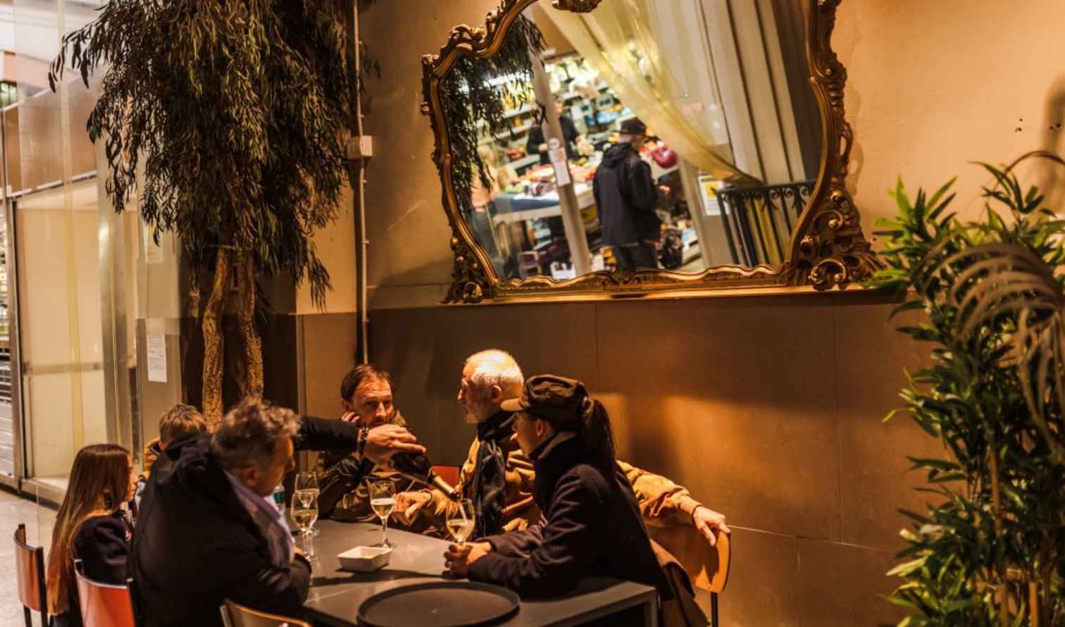 People seated at an outdoor cafe under a large mirror in Bologna