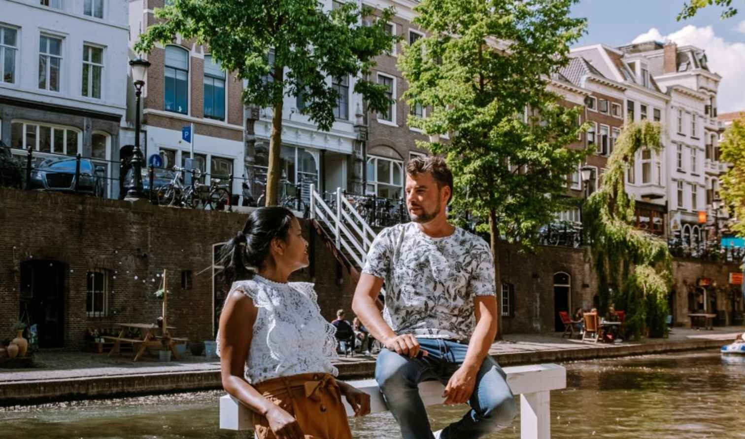 Two people sit by a canal in Utrecht, Netherlands.