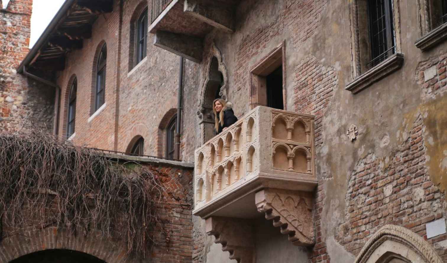 Person standing on Juliet's balcony in Verona, Italy.
