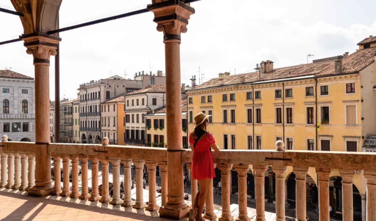 A person in a red dress stands on a balcony in Vicenza, Italy.