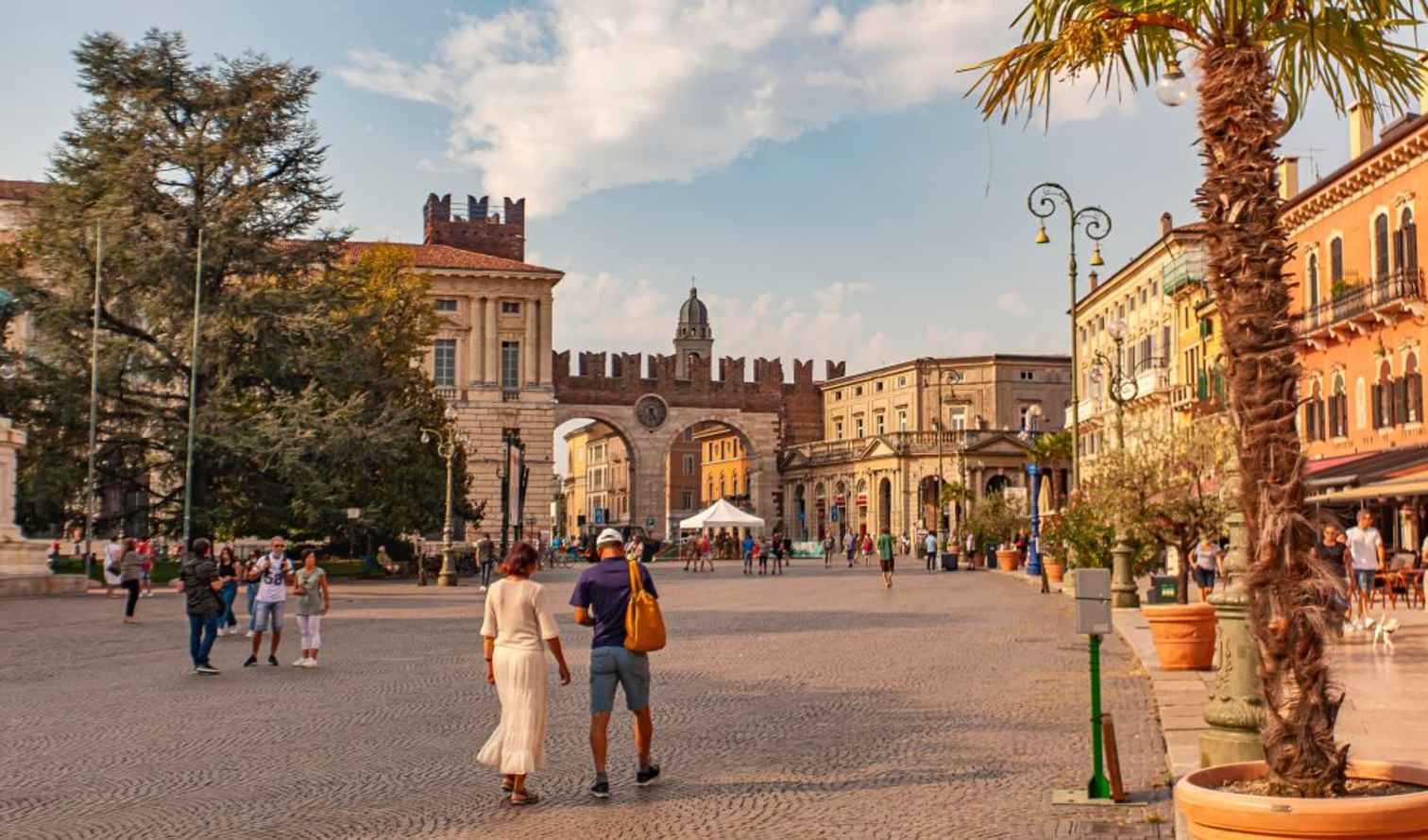 Visitors walk towards the stone arch in Verona's Piazza Bra.