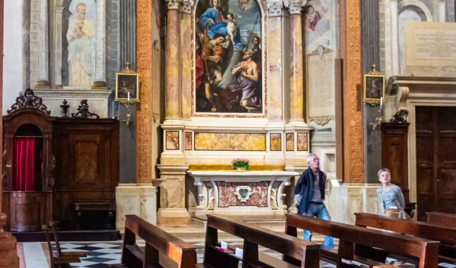 Two people walking inside the Church of the Carmini in Venice.