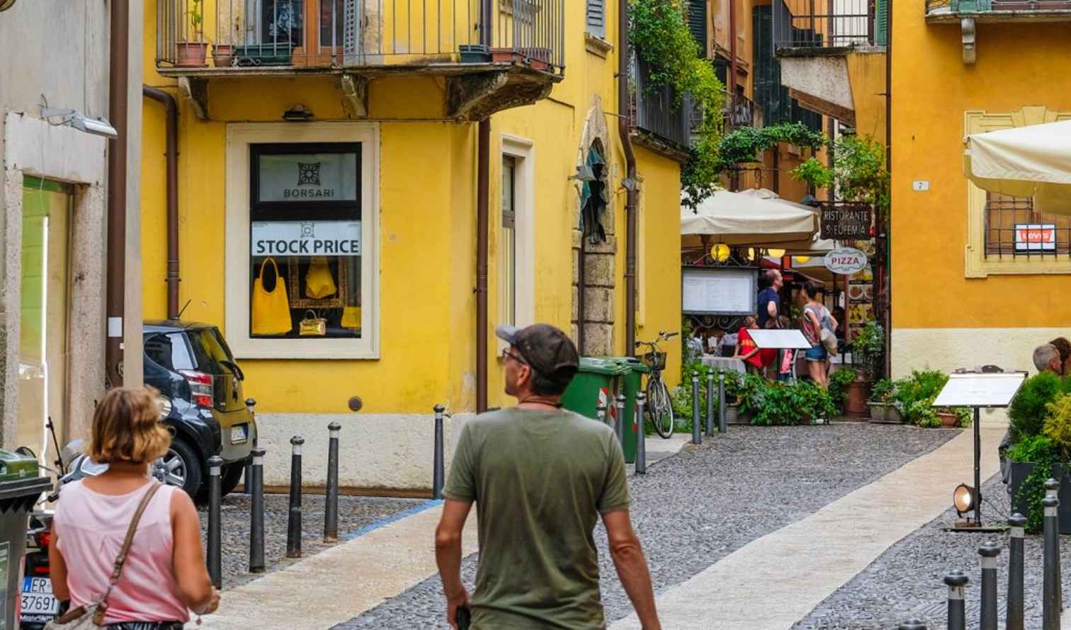 People walking in a narrow cobblestone street in Verona, Italy.