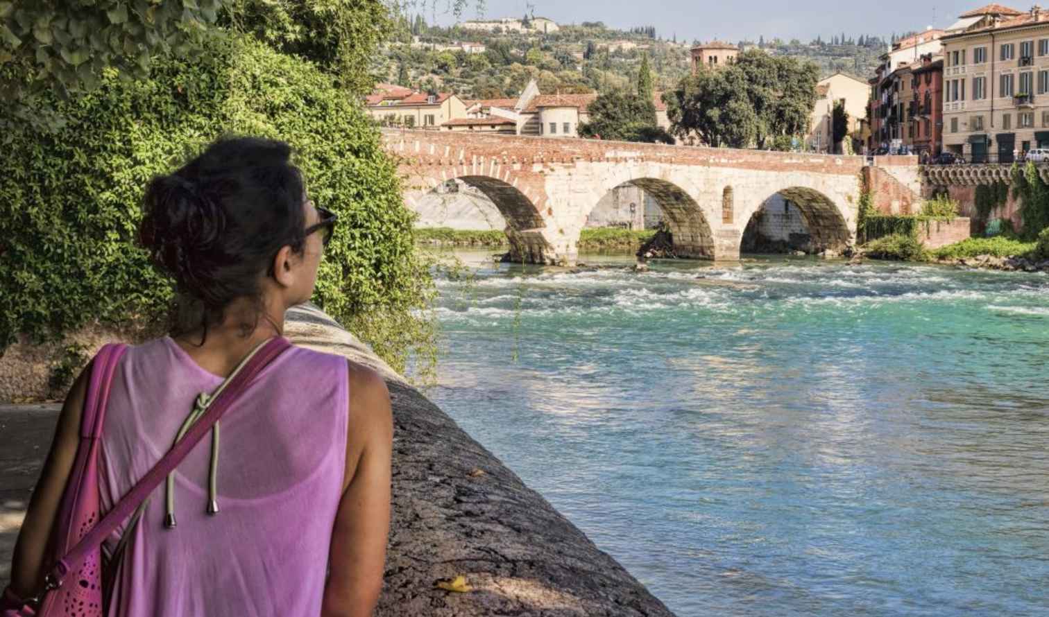 Person by the Adige River looking at Ponte Pietra in Verona.