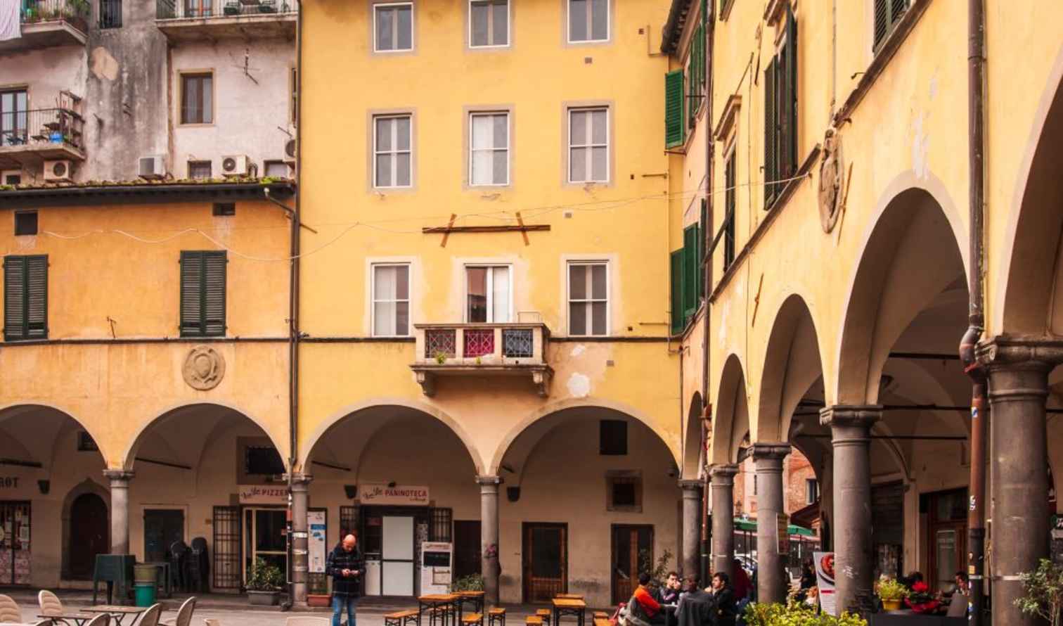 Yellow buildings with arched walkways in Piazza dell'Anfiteatro, Lucca.