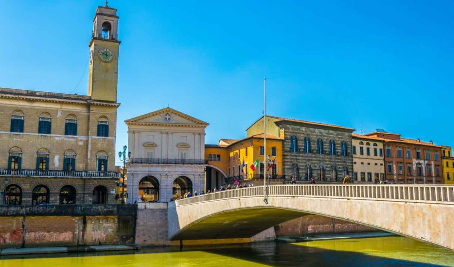 Clock tower and bridge seen in Pisa, Italy.