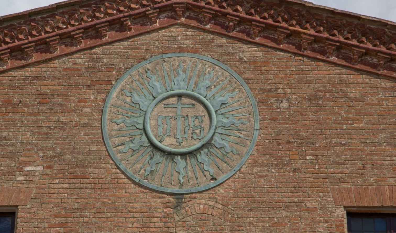 Facade of an Italian church with a Jesuit sunburst emblem in Siena