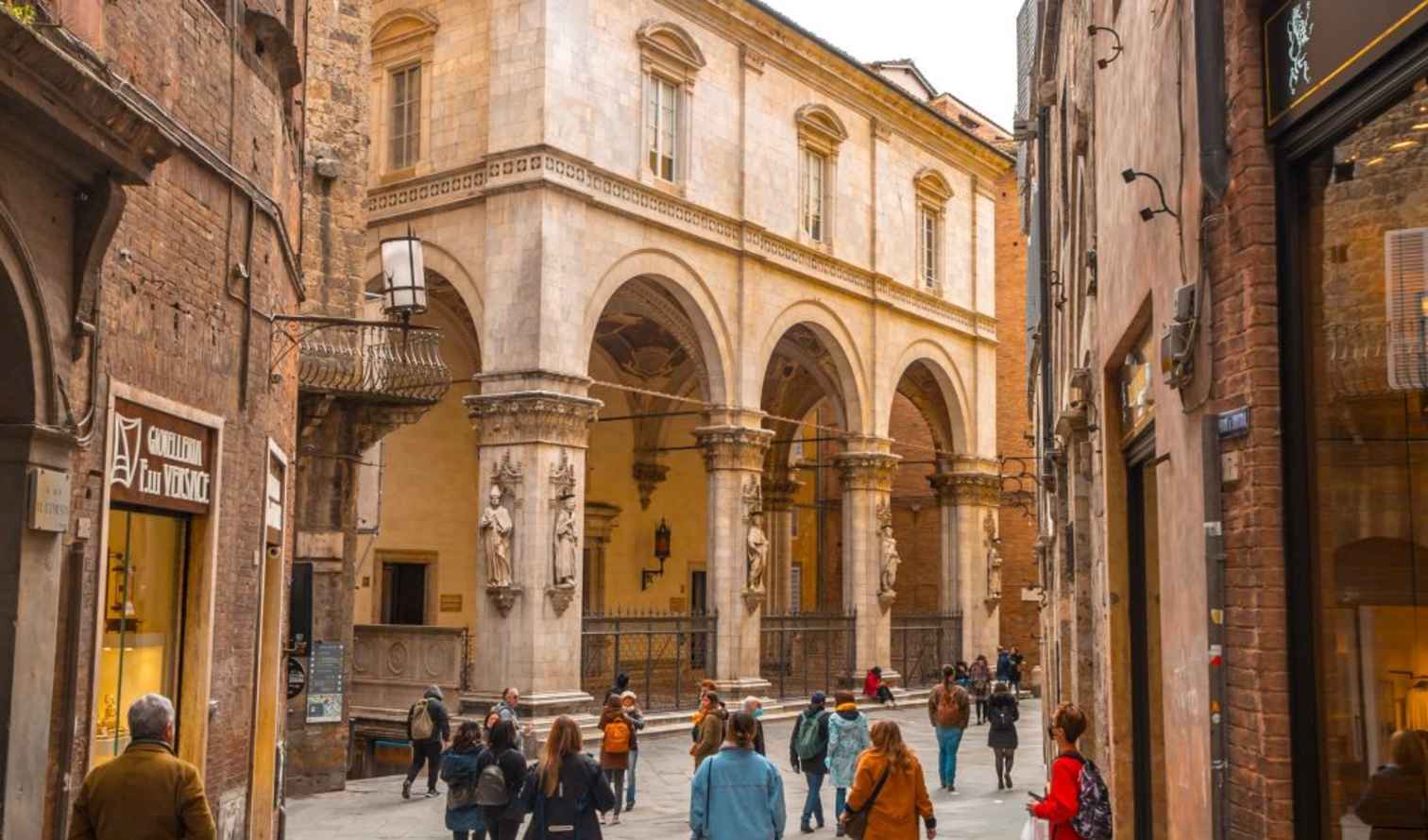 People walking past Loggia dei Mercanti in Siena, Italy.
