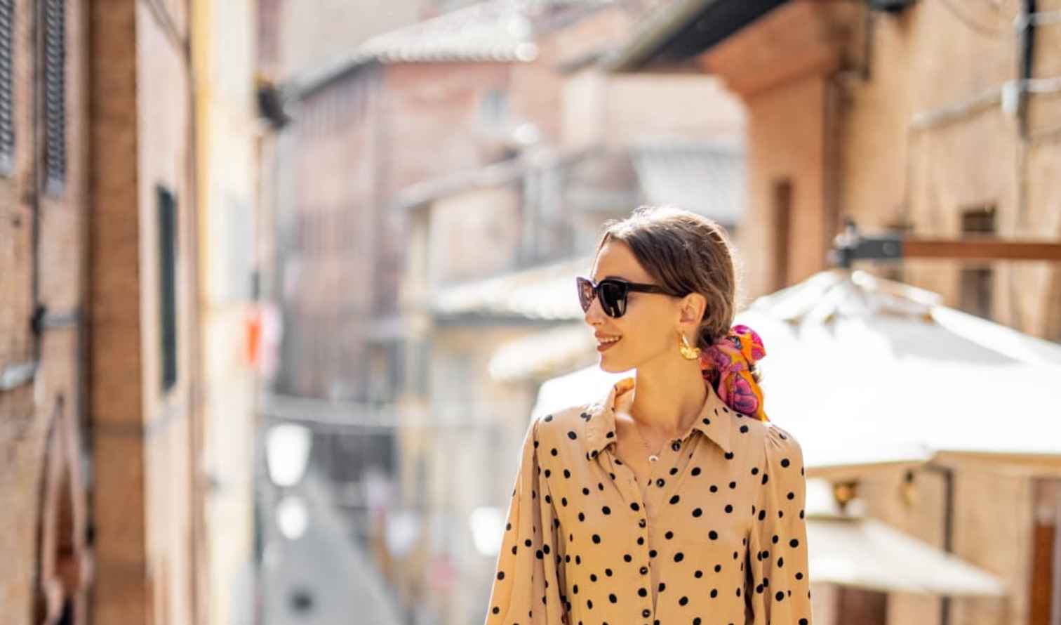 Woman in polka dot dress walking through a narrow street in Siena, Italy.