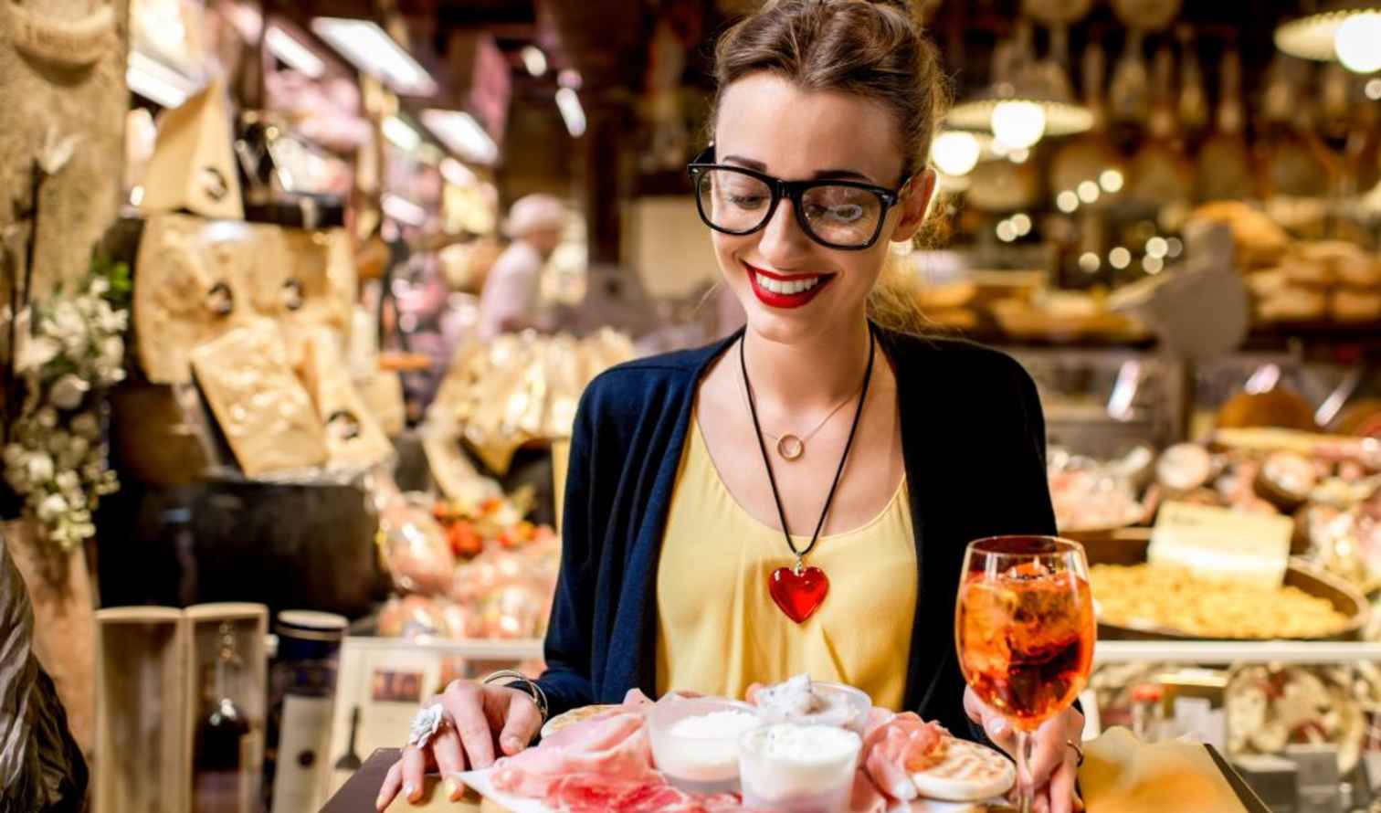 Woman with glasses holding a plate in a deli shop in Palermo