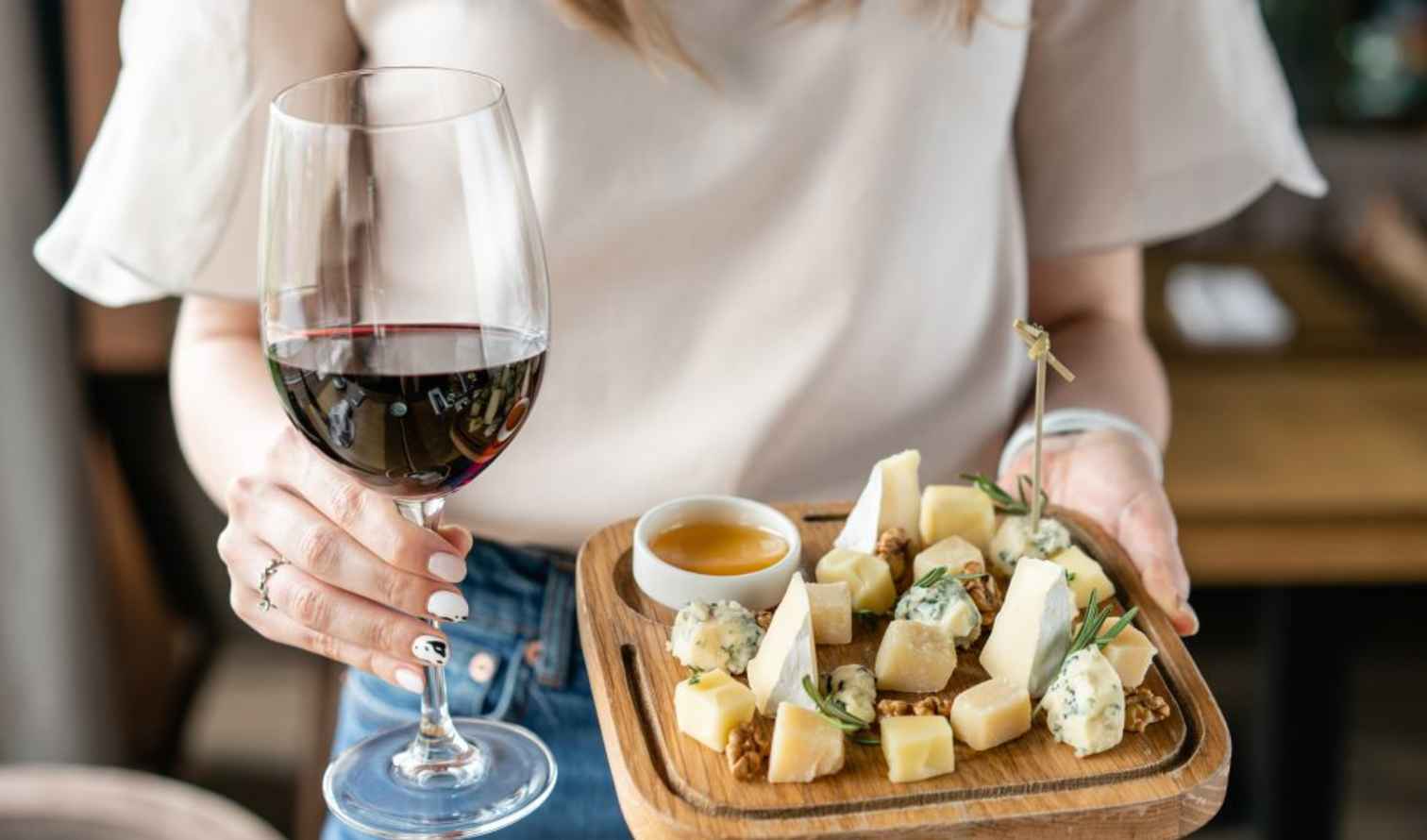 Person holding a wine glass and a cheese platter in Pisa.