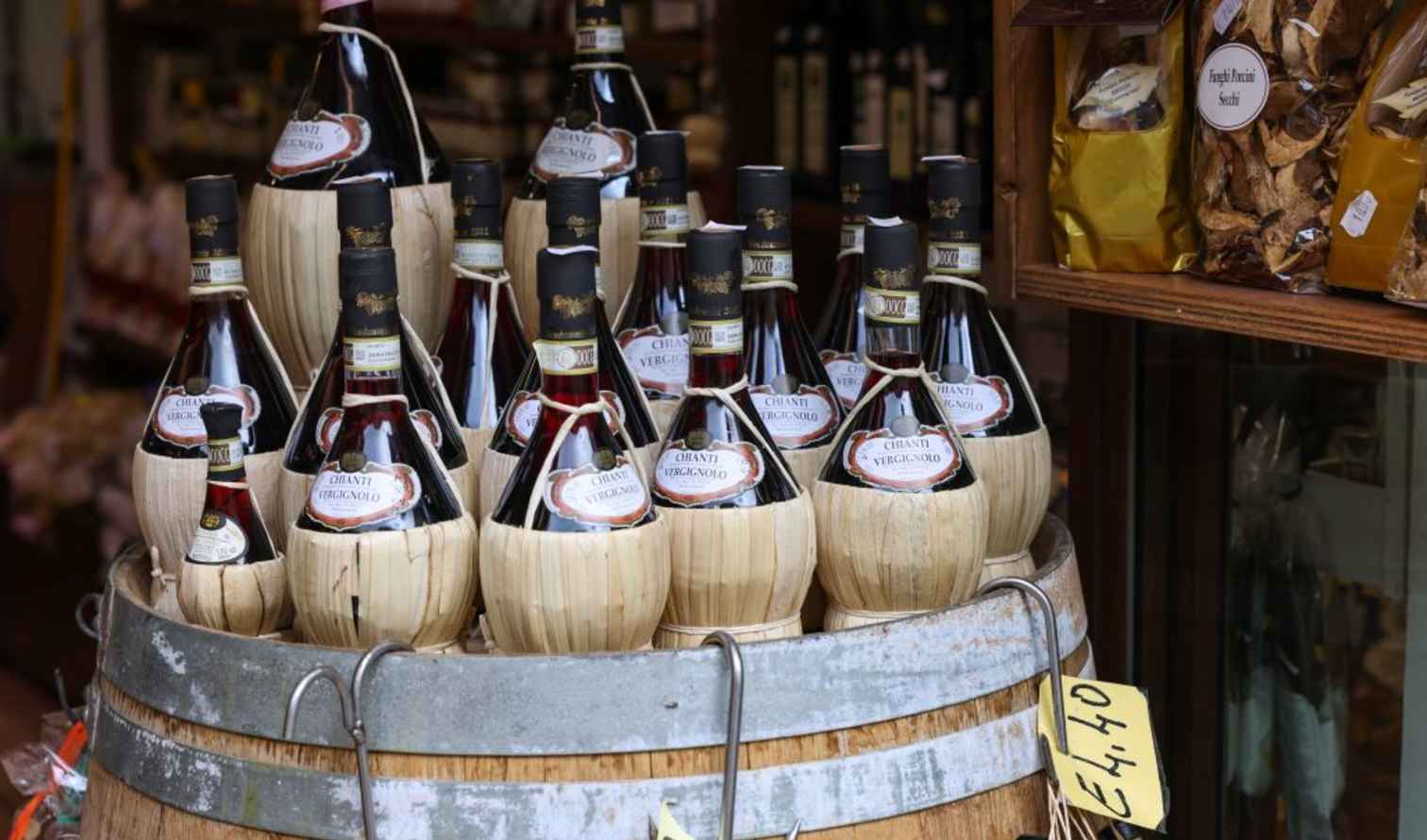 Chianti bottles displayed on a wooden barrel outside a shop in Sienna