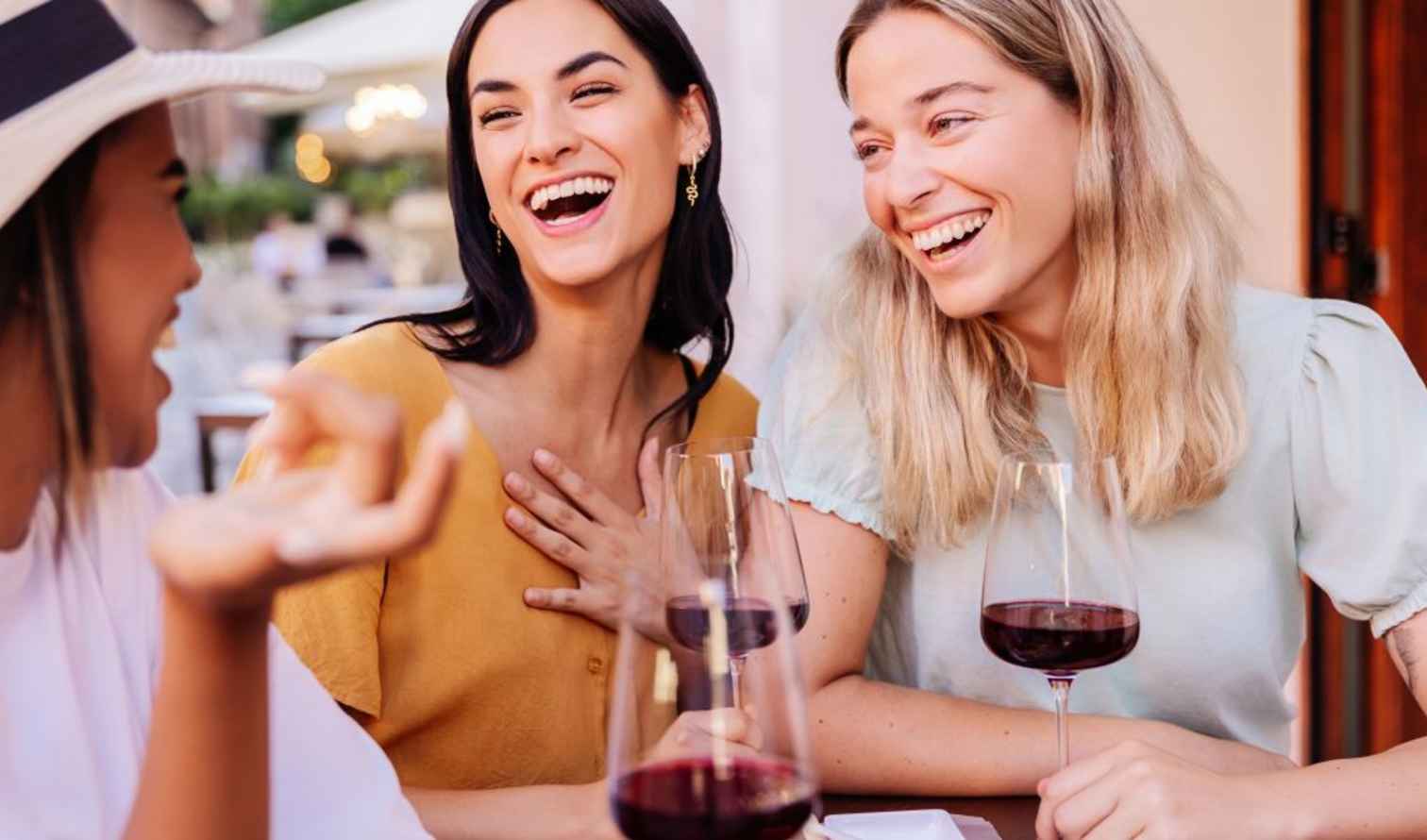 Three women sitting at an outdoor café table with wine glasses in Sienna