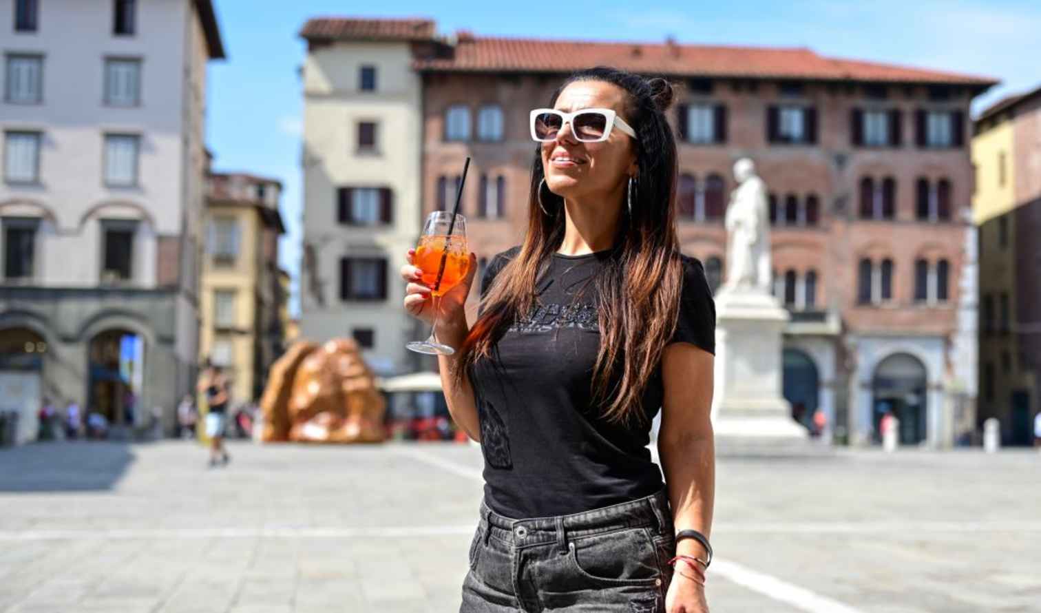 Woman with a drink in Piazza Anfiteatro, in Sienna