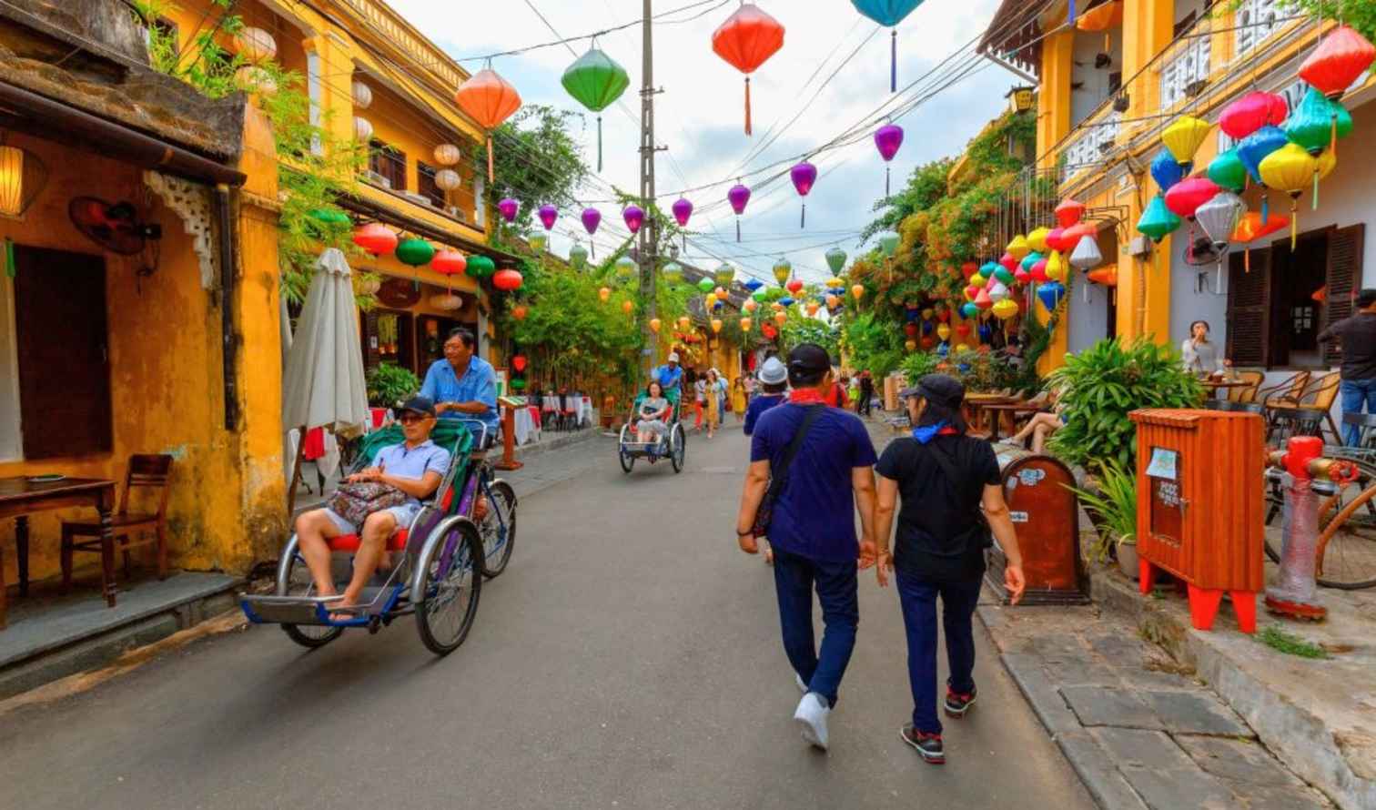 People walking and riding cyclos in Hoi An, Vietnam.