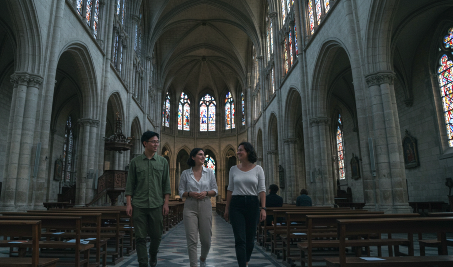 Cathedral interior featuring stained glass and Gothic architecture with visitors in Bordeaux 