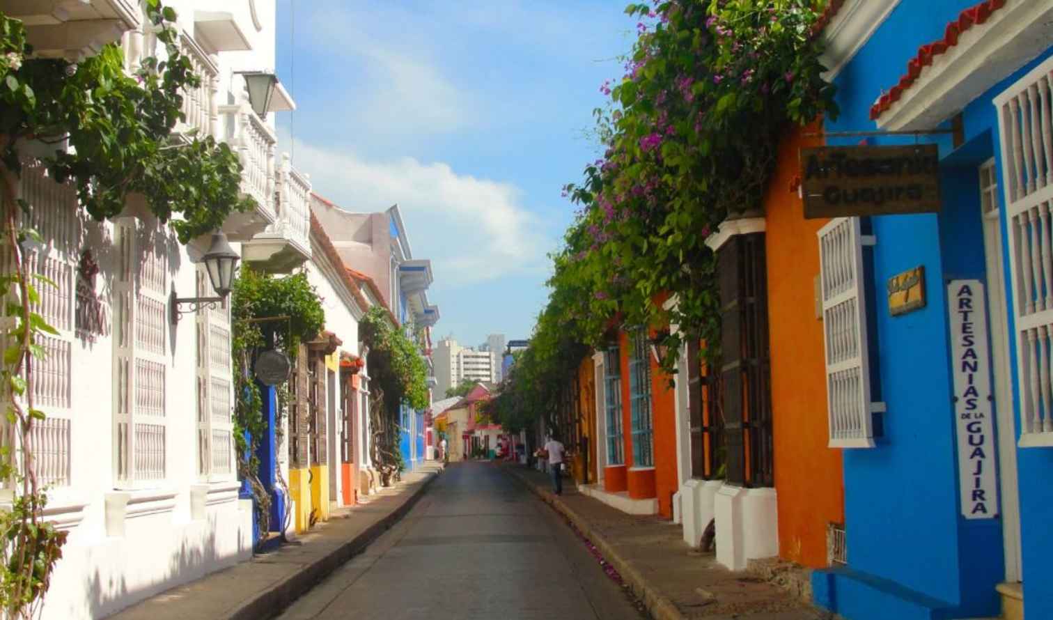 Colorful street in Getsemani, Cartagena, with vibrant painted buildings and greenery.