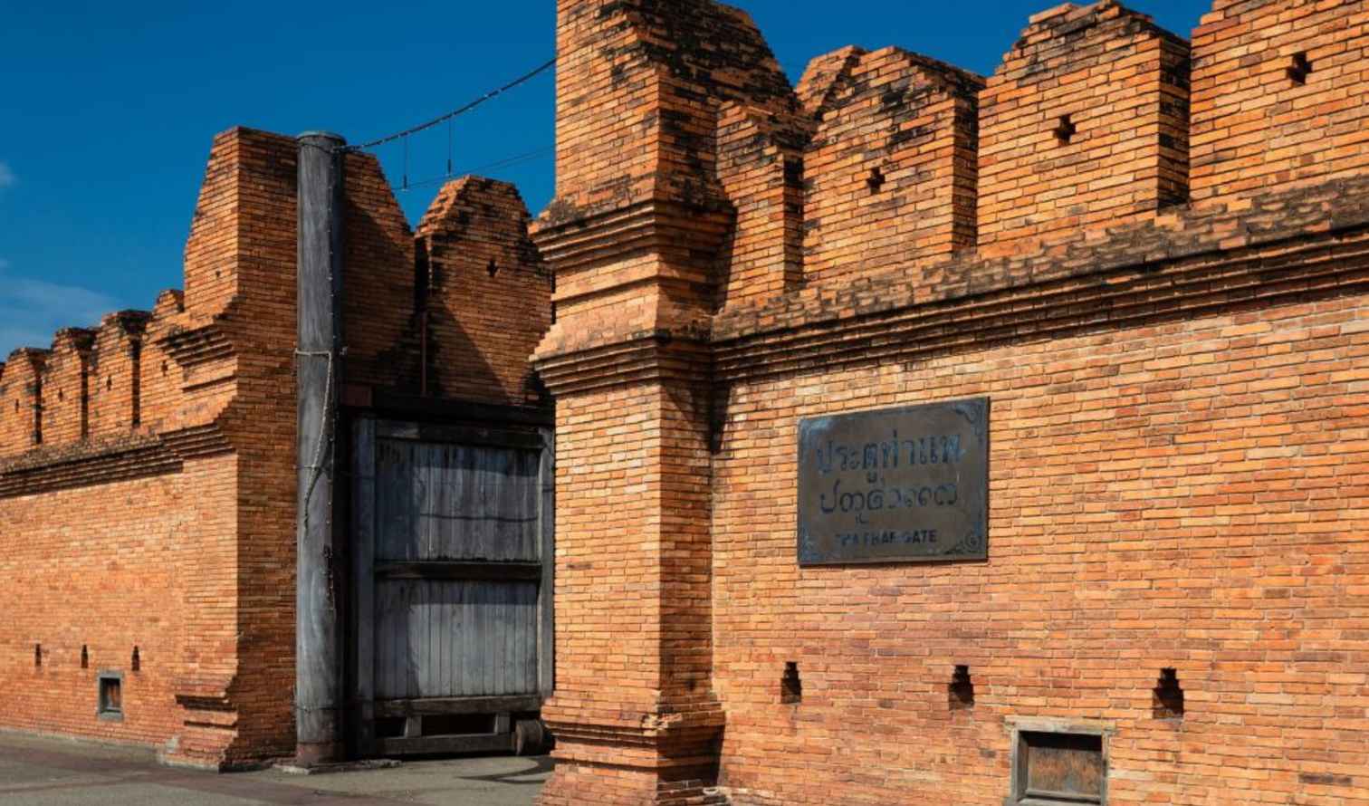 Tha Phae Gate brick wall with a wooden entrance in Chiang Mai.