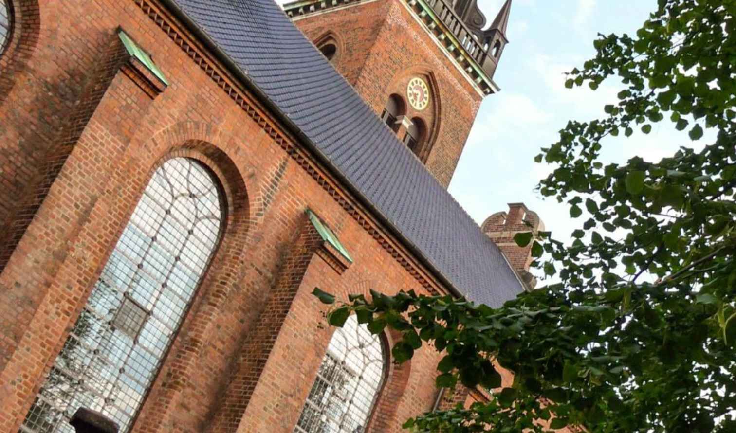Church exterior showing large windows and pointed tower in Copenhagen.