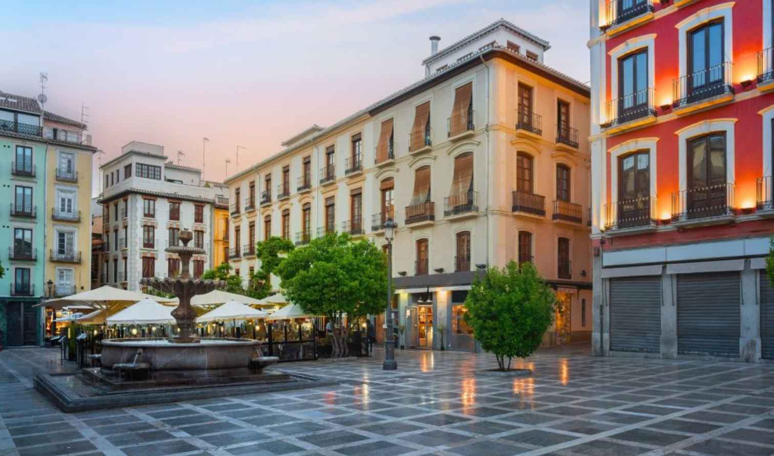 View of plaza with trees and buildings in Granada's city center.