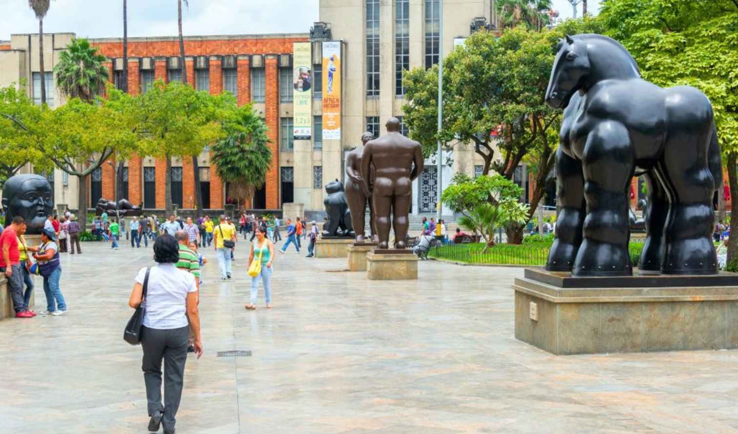 Visitors walking near Fernando Botero sculptures in a Medellín plaza.