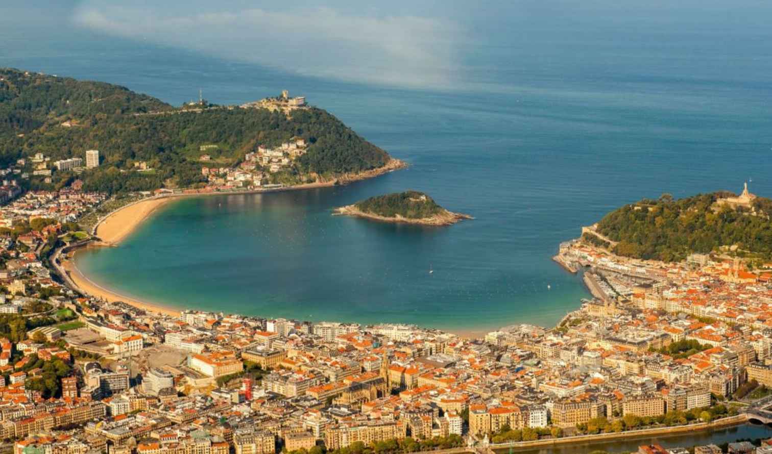 Aerial view of La Concha Bay in San Sebastián, Spain, with city buildings in foreground.
