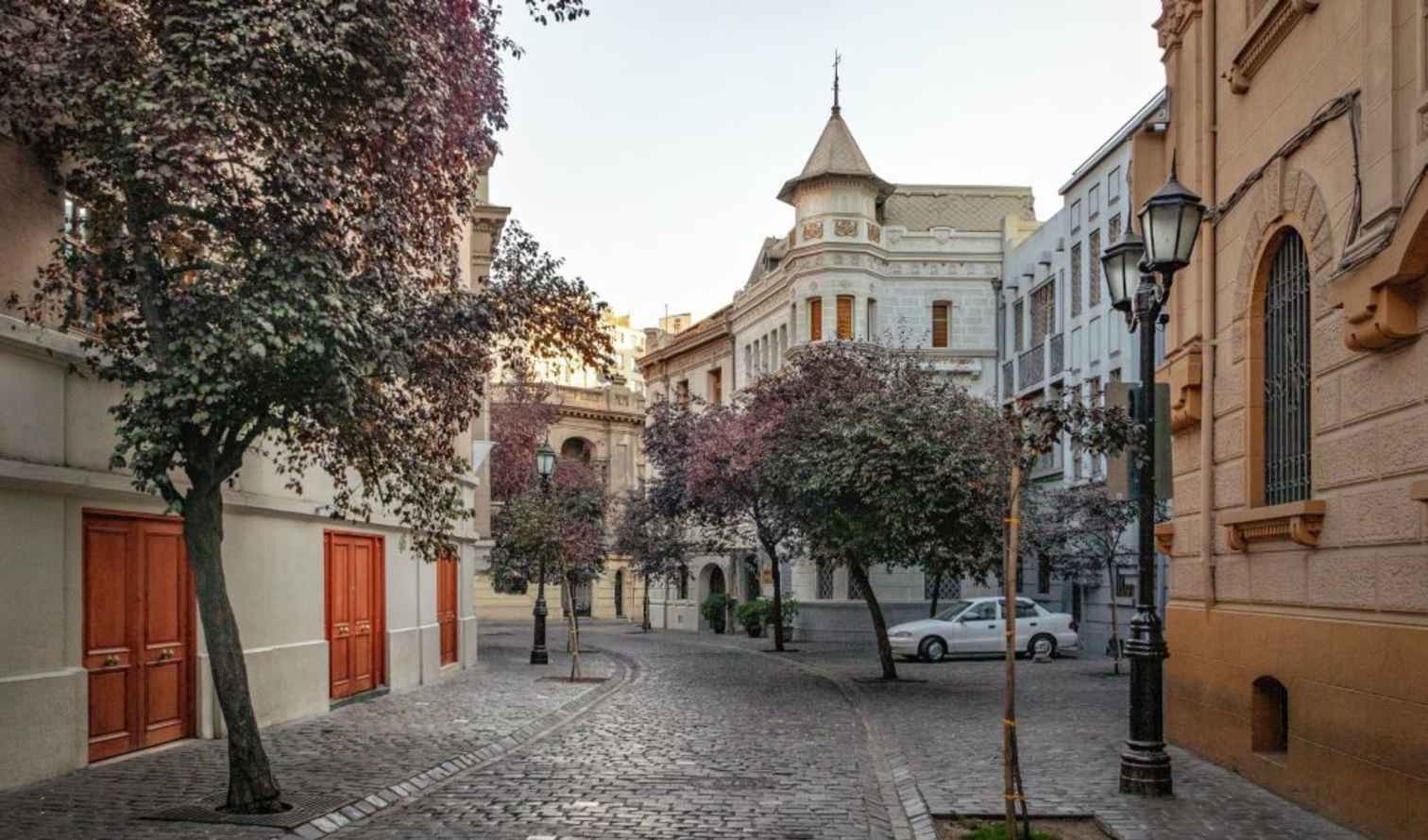 Cobblestone street in Barrio Paris-Londres, Santiago, Chile, lined with trees and historic buildings.