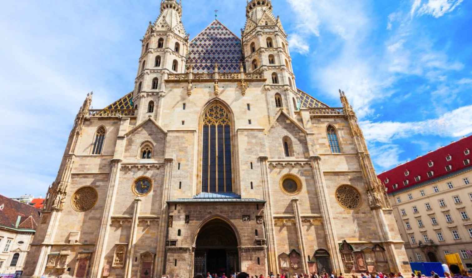 People gathering in front of St. Stephen's Cathedral, Vienna, under a blue sky.