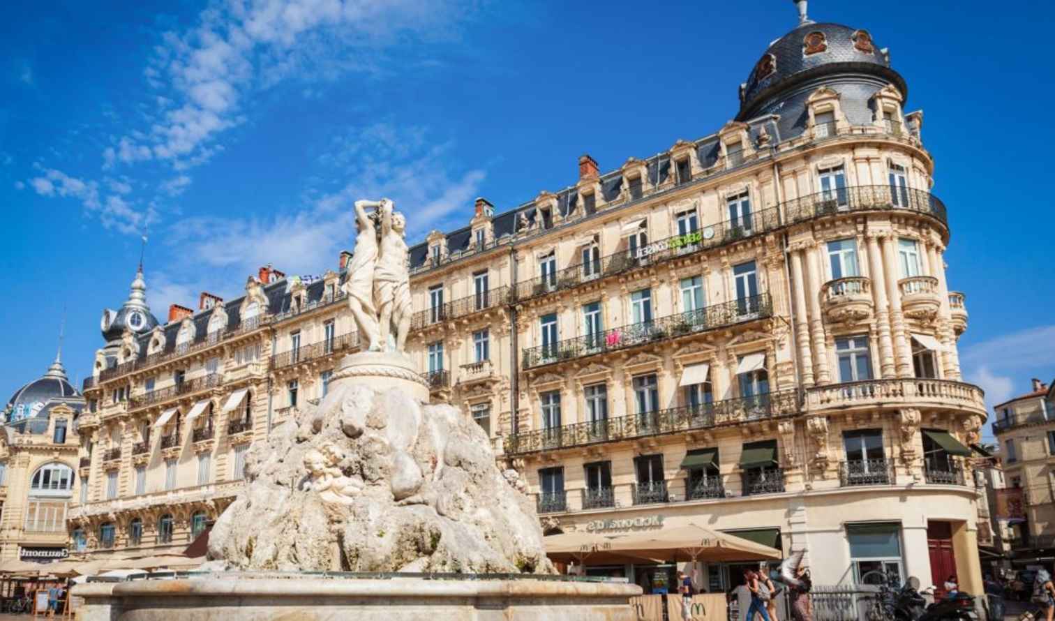 People walking near the stone fountain at Place de la Comédie, Montpellier.