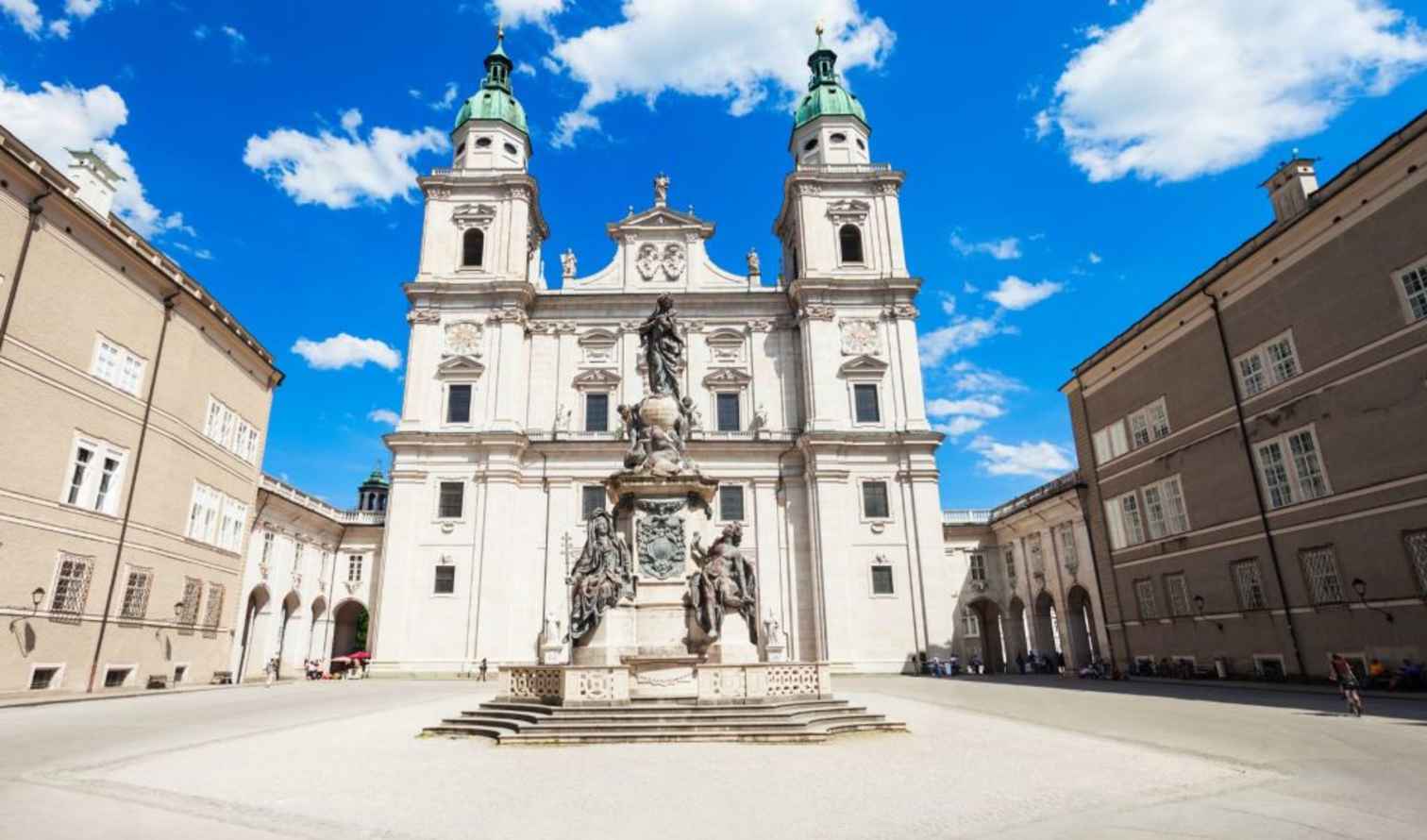 Front view of the Salzburg Cathedral and nearby buildings on a sunny day.