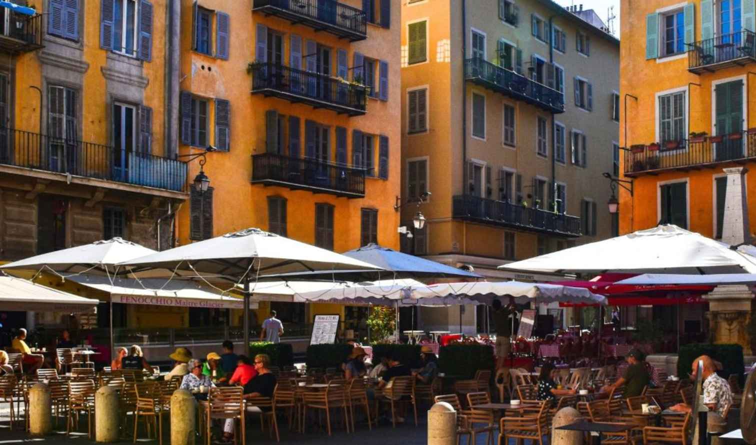 Cafe with outdoor seating on a narrow street lined with colorful buildings in Nice.