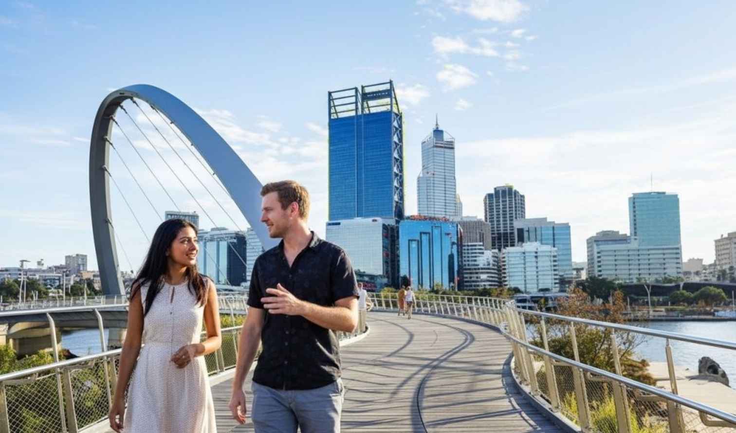 Couple walking on Elizabeth Quay Bridge with Perth skyline in the background.